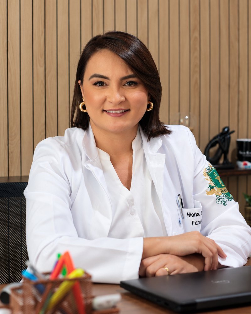 Rosi sorrindo em seu consultório, de jaleco branco